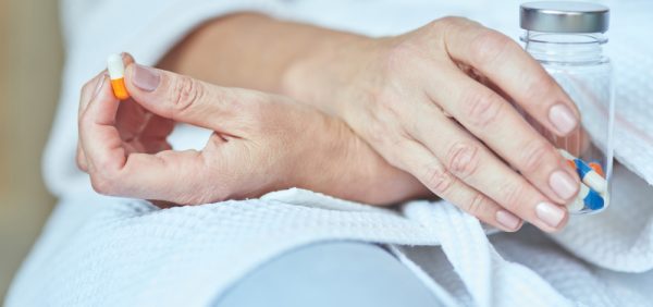 image of a dermatology patient holding a pill, thinking, perplexed, not sure about antibiotic resistance perhaps
