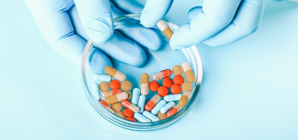 abstract image of various pills and researcher holding a pill