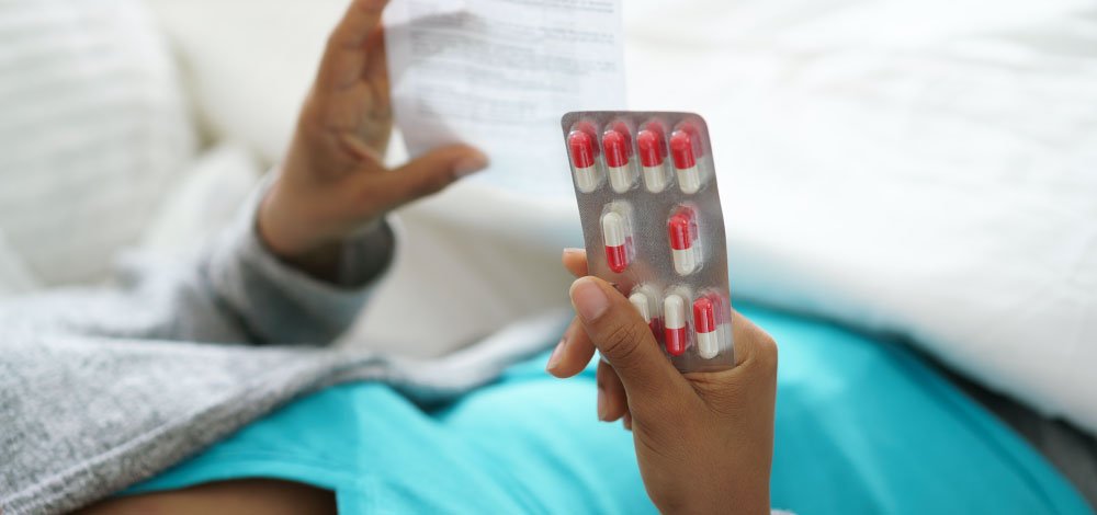 image of woman holding pills and reading instructions